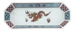 Travessa em porcelana oriental de formato oitavado, decorada com motivo oriental em policromia, destacando dragão central e bordas com elementos geométricos e florais. Peça de caráter decorativo, apresentando sinais de uso e marcas no verso. Mede 26 x 11 cm.