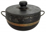 Panela antiga em pedra com tampa, estrutura reforçada com aro metálico e alças laterais em ferro. Peça robusta, de caráter utilitário, com interior cavado e exterior com pátina natural do tempo, evidenciando uso e autenticidade. Mede 29cm x 18cm.