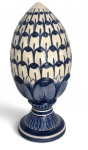Pinha em porcelana artística portuguesa, em formato clássico sobre base, decorada em azul sobre fundo marfim com motivos estilizados. Peça assinada na base Finas Artes 169, de caráter ornamental e tradição simbólica. Apresenta leves marcas do tempo. Mede 33cm.