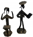 Par de esculturas judaicas em metal patinado, trabalho artesanal, representando figuras estilizadas possivelmente em cena ritual. Composição de linhas livres, bases recortadas e pátina escurecida pelo tempo. Peças de caráter simbólico e decorativo. Contém marcas do tempo. Medida do maior 23cm.