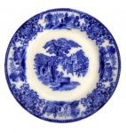 EUROPA SÉC. XIX - Prato raso em porcelana europeia dito azul borrão, decoração em azul sob esmalte com cena bucólica central e borda ornada com reservas figurativas e motivos florais. Verso com marca de manufatura. Apresenta craquelê do tempo. Meados séc. XIX. Mede 18 cm.