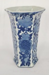 Vaso em porcelana esmaltada, de formato sextavado, com decoração em azul sobre fundo branco, apresentando motivos florais estilizados e elementos orgânicos. Borda levemente alargada. Base com selo em caracteres orientais. Medidas: 20 cm (altura) x 14 cm (largura aproximada). 