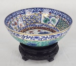 Schmidt. Centro de mesa em porcelana nacional esmaltada, decorada com flores e elementos geométricos. Acompanha peanha em madeira. Medindo: 10 x 26 cm (centro) e 6 x 16 cm.  Base do centro com lascas que não interfere na beleza e uso da peça. 