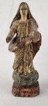 Imagem sacra em madeira entalhada e policromada, representando santa mártir com palma, símbolo do martírio. Peça de caráter devocional, com rica pátina e desgastes compatíveis com o tempo. Altura: 25 cm.