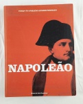 Catálogo de arte intitulado Napoleão, dedicado à trajetória e ao imaginário histórico de Napoleão Bonaparte, publicado pela Fundação Armando Alvares Penteado, por meio do Museu de Arte Brasileira. A obra reúne imagens, documentos e peças relacionadas ao período napoleônico, com abordagem histórica e artística. Exemplar em capa dura, com projeto gráfico em fundo vermelho e retrato estilizado na capa. Apresenta sinais de manuseio nas bordas e cantos, compatíveis com o uso. 