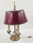 Luminária de mesa em metal com acabamento em bronze, medindo aproximadamente 58 cm de altura, com estrutura clássica composta por base circular, haste central e três braços para lâmpadas. Possui cúpula em tom vermelho. Necessita revisão na parte elétrica, incluindo desgaste na pintura da cúpula e oxidação leve no metal, compatíveis com a idade. 