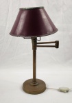 Luminária de mesa em metal com acabamento em bronze, medindo aproximadamente 55 cm de altura, com base circular e corpo central sustentando três braços para lâmpadas. Apresenta cúpula em metal pintado na cor vermelha, com design clássico e elemento decorativo superior. Fiação aparente com interruptor no cabo. Peça com sinais de uso e pátina do tempo, incluindo desgaste na pintura da cúpula e oxidação leve no metal, compatíveis com a idade. 