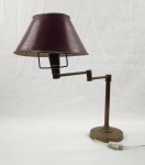 Luminária de mesa articulada em metal com acabamento em bronze, medindo aproximadamente 48 cm de altura, com base circular e braço móvel que permite ajuste de posição. Possui cúpula metálica em tom vermelho, de formato cônico, Fiação com interruptor no cabo necessário revisão, incluindo desgaste na pintura da cúpula e oxidação leve no metal, compatíveis com a idade. 