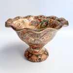 Centro de mesa em porcelana chinesa, medalhão central com cena oriental do cotidiano em rica policromia, pontilhados em relevo e bordas onduladas. Med 17 cm altura 24 cm diâmetro. 