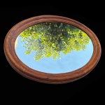 Espelho oval com moldura em madeira nobre em frisos. Década de 60. Pequena oxidação. Med 67x49cm. 