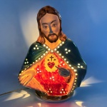 Sagrado Coração de Jesus - Imagem com iluminação representando Jesus, confeccionado em porcelana com rica policromia. Luminária possui fenestrados para saída de luz. Med 27 cm x 22 cm.