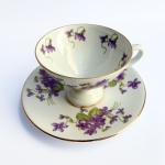 Linda xícara de coleção para chá em porcelana branca vitrificada decorada por flores na cor lavanda com filetes à ouro.