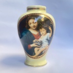 Vaso em porcelana alemã de manufatura DP (Deustche Porzellan) retratando cena de Maria e menino Jesus em linda policromia sobre fundo bege com filetes à ouro. Med 26 cm. 
