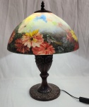 Luminária de mesa/abajur Art Nouveau, origem EUA, com base metálica escura toda
ornamentada em relevo com cúpula em pasta de vidro floral ao gosto Handel.
Funciona. Acompanha lâmpada, medindo 27,5cm.