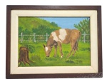 ROBERTO 87 -  Pintura a óleo sobre a tela, emoldurada que retrata um cavalo com pelagem malhada pastando em um campo verde com uma cerca de madeira ao fundo. com paisagem rural. Medindo  35 x 24 cm.