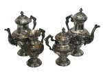 Elegante jogo de chá em metal espessurado a prata, composto por bule de chá, bule de café, açucareiro e leiteira, todos ricamente ornamentados com decoração em relevo de inspiração rococó, apresentando alças trabalhadas, bicos curvos e tampas com pega torneada. Apresenta desgastes no banho de prata. Medidas: bule de chá 23 x 28 x 13 cm; bule de café 23,5 x 27 x 14 cm; açucareiro 20 x 12 x 20,5 cm; leiteira 15 x 19 x 10,5 cm.