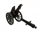 Antiga miniatura de canhão em metal e madeira, composta por estrutura com rodas raiadas, suporte articulado e canhão removível. Peça de caráter decorativo e colecionável, reproduzindo modelo de artilharia antiga com riqueza de detalhes construtivos. Medidas: estrutura 19 x 13 x 12 cm; canhão 19,5 x 7 x 3,5 cm.