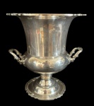 Elegante champanheira em metal espessurado a prata 90, com corpo bojudo sobre pedestal e alças laterais ricamente trabalhadas. Medidas: 24 x 27 cm.