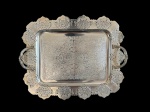 Antiga bandeja em metal espessurado a prata, de formato retangular, apresentando rica decoração rendilhada vazada nas bordas e centro ornamentado com delicados arabescos gravados. Possui alças laterais trabalhadas. Medidas: 30,5 x 37,5 x 1,5 cm.