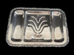Antiga bandeja em metal espessurado a prata, de formato retangular, apresentando compartimentos internos e rica decoração em relevo ao centro, além de bordas ornamentadas com delicados motivos florais. Medidas: 49,5 x 34,5 x 4,5 cm..