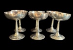 Conjunto composto por 6 elegantes taças em metal espessurado a prata, com bojo liso apoiado sobre haste torneada e base circular. Peças de linhas clássicas, próprias para sobremesas, coquetéis ou uso decorativo à mesa. Apresentam sinais naturais do tempo e do uso, Med.: 11,5 x 9 cm cada.