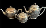 Conjunto composto por três peças em metal espessurado a prata, de elegante desenho canelado, sendo um bule para chá, um bule para café e um açucareiro com tampa, todos com acabamento refinado, pegadores geométricos e tampas decoradas em relevo radial, no  estilo Art Déco. As peças apresentam sinais naturais do uso e do tempo, observando-se que um dos bules necessita de restauração na tampa. Medidas: bule para chá 25 x 12 x 14,5 cm; bule para café 25,5 x 19 x 11 cm; açucareiro 17,5 x 10 x 11,5 cm.