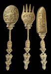 Colher, garfo e espátula  em bronze, em grandes proporções, com ricos relevos figurativos e ornamentação em estilo europeu tradicional, apresentando detalhes em cenas campestres e elementos heráldicos em relevo, além de furação para fixação. Medidas variando entre 34,5 e 36 cm de comprimento.