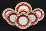 Meito, Japan. Conjunto composto de prato para bolo e seis pratos para sobremesa em porcelana japonesa esmaltada, pintados à mão, com interior em tom vinho e rica decoração em arabescos com detalhes em ouro. Manufatura no verso. Medindo: 27 cm (prato para bolo).