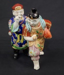 Porcelana oriental. Escultura em porcelana esmaltada representando figuras orientais em composição, com rica decoração em policromia e detalhes em ouro. Manufatura no verso. Altura: 19 cm. Observação: Necessita restauro no pé direito.