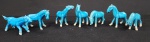 Conjunto decorativo composto por 7 esculturas de cavalos em cerâmica azul esmaltada, moldados em posições variadas de movimento, com detalhes estilizados e acabamento brilhante, peças de caráter ornamental, apresentando pequenas variações de tonalidade e sinais leves de uso.