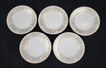 Noritake, Japan. Cinco pratos para pão em porcelana japonesa esmaltada na cor branca, modelo Raphael, com rica decoração de flores, volutas e filetes em ouro. Manufatura no verso. Medindo: 16 cm.