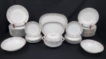 Schmidt, Brasil. Serviço para jantar em porcelana esmaltada na cor branca, com delicada decoração floral em tons de lilás e verde, ornada com frisos e filetes dourados. Composto por uma sopeira com tampa, duas travessas redondas, duas travessas ovais, doze pratos rasos, doze pratos fundos e onze pratos para sobremesa. Manufatura no verso.Um prato fundo com lasca, dois pratos de sobremesa com bicados e um prato raso com fio de cabelo.