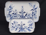 Steatita, Brasil. Duas travessas/bandejas em porcelana esmaltada, com decoração floral azul estilo cebolinha. Manufatura no verso. Medindo: 41 x 24 cm e 28,5 x 17 cm. Uma com lasca.