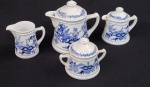 Steatita, Brasil. Quatro peças para servir em porcelana esmaltada, com decoração floral azul estilo cebolinha. Composto de 2 bules, leiteira e açucareiro. Manufatura no verso. Medindo: 19 x 20 cm, 15 x 15cm, 11 x 13 cm, 13 x 17 cm. um bule com fio de cabelo.