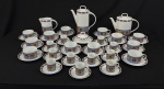 Schmidt, Brasil. Conjunto para chá e café em porcelana esmaltada, decorado em policromia, composto por um bule de café, um bule de chá, uma leiteira, uma manteigueira, doze xícaras de chá com seus respectivos pires e onze xícaras de café com seus respectivos pires. Manufatura no verso. Medindo: 24 x 20 cm, 19 x 23 cm, 13 x 15 cm e 8 x 16 cm. Observação: 2 pires e 2 xícaras de chá com bicados e 1 xícara de café com bicados.