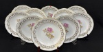 Porcelana Schmidt. Dez belíssimos pratos fundos em porcelana esmaltada, decorados com motivos florais e ricos detalhes em ouro. Bordas onduladas, ramos nas extremidades em relevo e filetes em ouro Manufatura no verso. Medindo: 4 x 23 cm. Um com bicado.