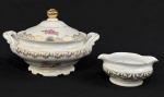 Porcelana Schmidt. Sopeira e molheira em porcelana esmaltada, decorados com motivos florais e ricos detalhes em ouro. Bordas onduladas, ramos nas extremidades em relevo e filetes em ouro Manufatura no verso. Medindo: 22 x 30 x 26 cm e 7 x 17 cm. Quebra na borda da sopeira (ver foto extra).