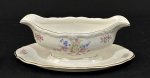 C. Tielsch & Co., Polônia, década de 1940. Molheira em porcelana esmaltada na cor branca, decorados com ramalhetes florais em policromia, frisos dourados e bordas onduladas. Manufatura no verso. Medindo: 10 x 24 x 16 cm.