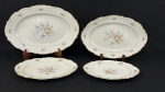 C. Tielsch & Co., Polônia, década de 1940. Quatro travessas ovais e uma travessa redonda em porcelana esmaltada na cor branca, decoradas com ramalhetes florais em policromia, frisos dourados e bordas onduladas. Manufatura no verso. Medindo:29 x 20 cm (menor) e 42,5 x 29 cm (maior) Menor com lasca.