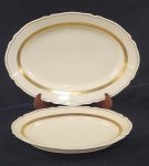 Vista Alegre, Portugal. Duas travessas em porcelana portuguesa esmaltada na cor creme, com frisos em ouro. Manufatura no verso. Medindo: 4 x 23 x 33cm e 5 x 40 x 28 cm. 