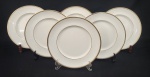 Royal Doulton, England. Seis pratos rasos em porcelana inglesa esmaltada na cor branca, com frisos em ouro. Manufatura no verso. Medindo: 26,5 cm.