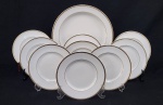Royal Doulton, England. Conjunto de prato de bolo e oito pratos para sobremesa em porcelana inglesa esmaltada na cor branca, com frisos em ouro. Manufatura no verso. Medindo: 20 cm e 31 cm.