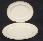 Royal Doulton, England. Duas travessas em porcelana inglesa esmaltada na cor branca, com frisos em ouro. Manufatura no verso. Medindo: 3 x 38 x 31 cm e 32 x 26 cm.