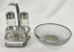 Galheteiro em inox da marca Tramontina com recipientes em vidro e cesta para pães em metal prateado. Medindo: 20 x 20 cm e 21 x 15cm.