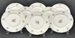 Oito pratos rasos em porcelana da República Tcheca, esmaltados na cor branca, decoração floral policroma e filetes em ouro, bordas com ramos em relevo. Med. 24,5 cm diâm.