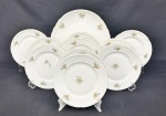 Conjunto para bolo em porcelana da República Tcheca, esmaltado na cor branca, decoração floral policroma e filetes em ouro, bordas com ramos em relevo, composto de prato para bolo e 10 pratinhos. Med. 29 cm e 17 cm diâm. Três com fio de cabelo.