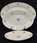 Três travessas em porcelana da República Tcheca, esmaltadas na cor branca, decoração floral policroma e filetes em ouro, bordas com ramos em relevo. Med. 18 x 28 cm à 27 x 40 cm. Uma com fio de cabelo.