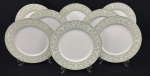 Sango China, Japão. Oito pratos rasos em porcelana japonesa esmaltada na cor branca, decoração floral sobre fundo verde e filetes em prata. Manufatura no verso. Med. aprox. 27 cm diâm. 
