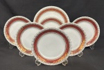 Steatita. Conjunto para sobremesa, com prato para bolo e 6 para sobremesa em porcelana nacional esmaltada, decoração com larga faixa na tonalidade vinho, enriquecida por minuciosos ornamentos geométricos e arabescos, ricamente realçados a ouro, sobre fundo branco. Manufatura no verso. Medindo; 19 cm e 26 cm.