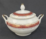Steatita. Sopeira em porcelana nacional esmaltada, decoração com larga faixa na tonalidade vinho, enriquecida por minuciosos ornamentos geométricos e arabescos, ricamente realçados a ouro, sobre fundo branco. Manufatura no verso. Medindo; 20 x 26 x 21 cm.